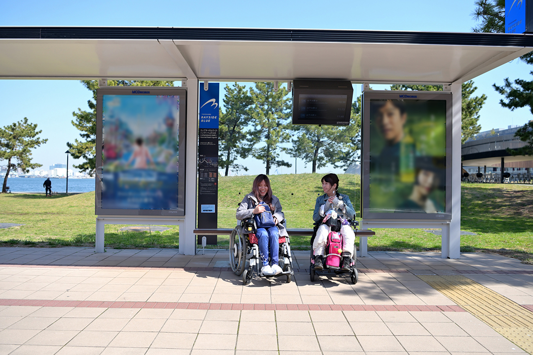 モデル二人がバス停留所で横浜市営ベイサイドブルーバスを待っている様子