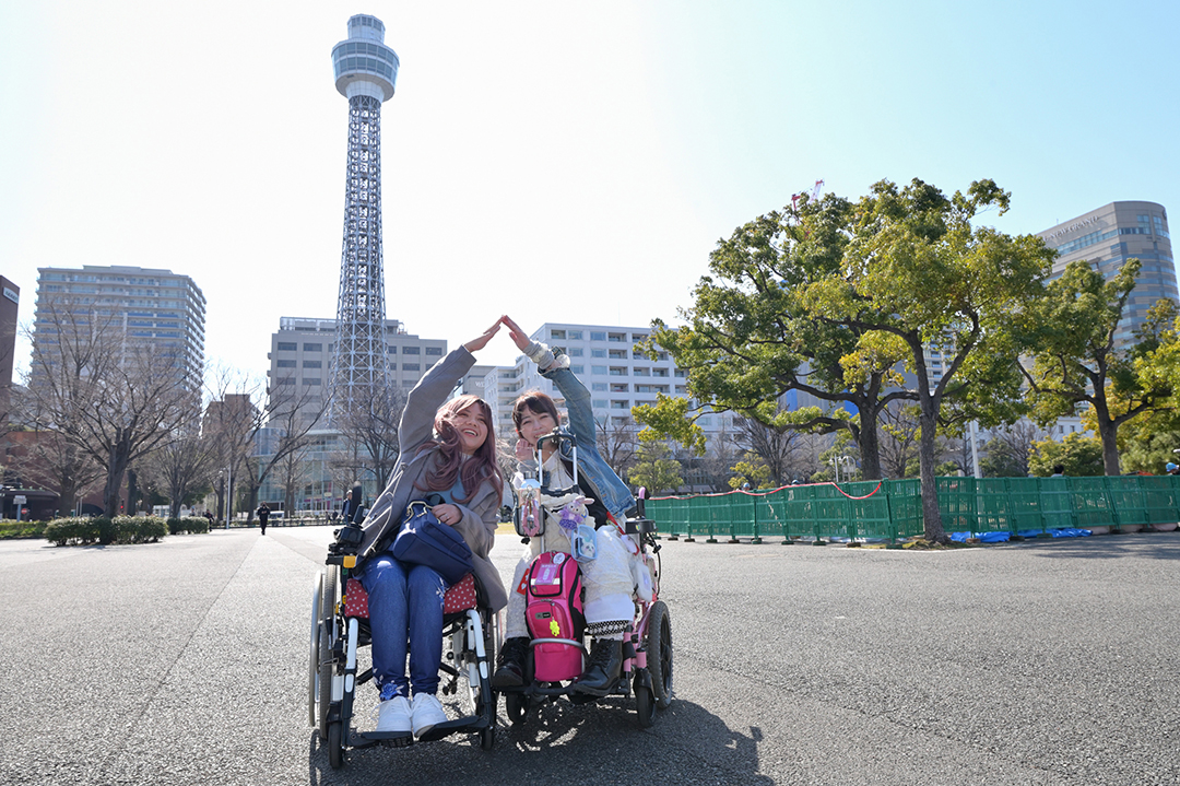 山下公園からバックに見えてきた横浜マリンタワーのポーズをしているモデル二人