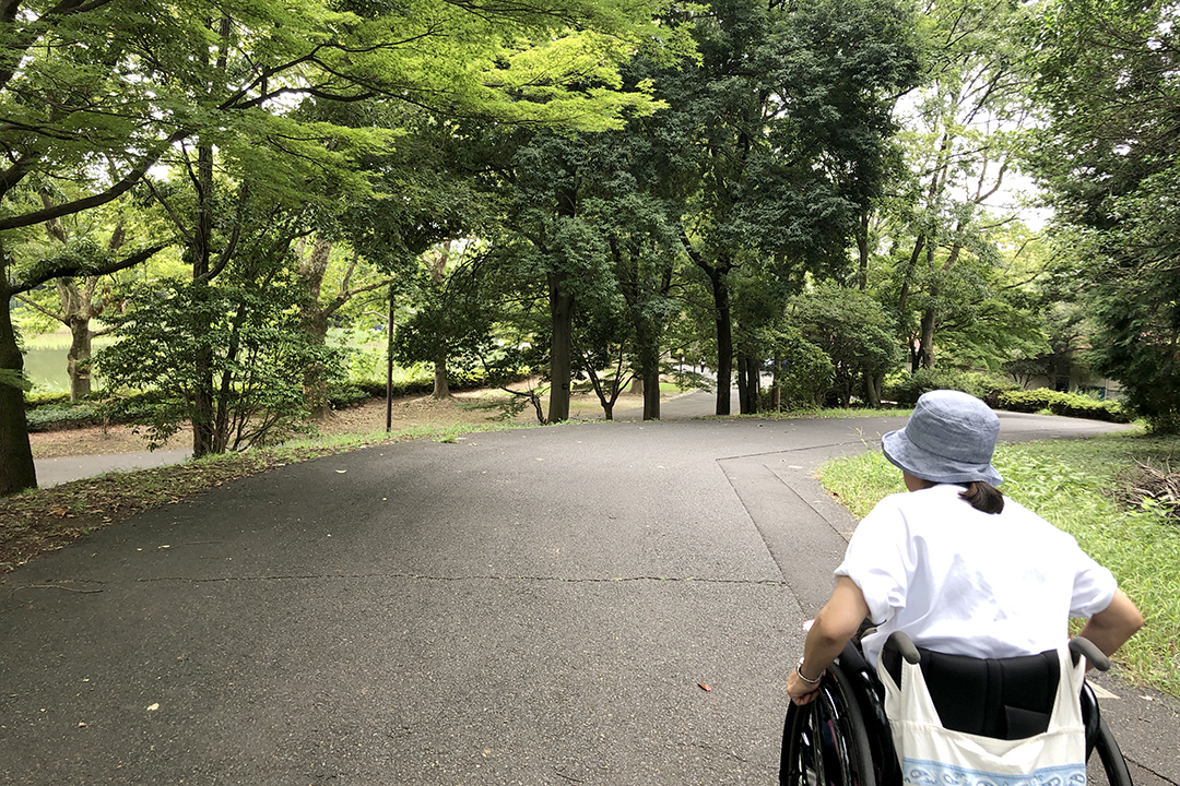 車いすの女性が勾配のキツイ道を下っている写真