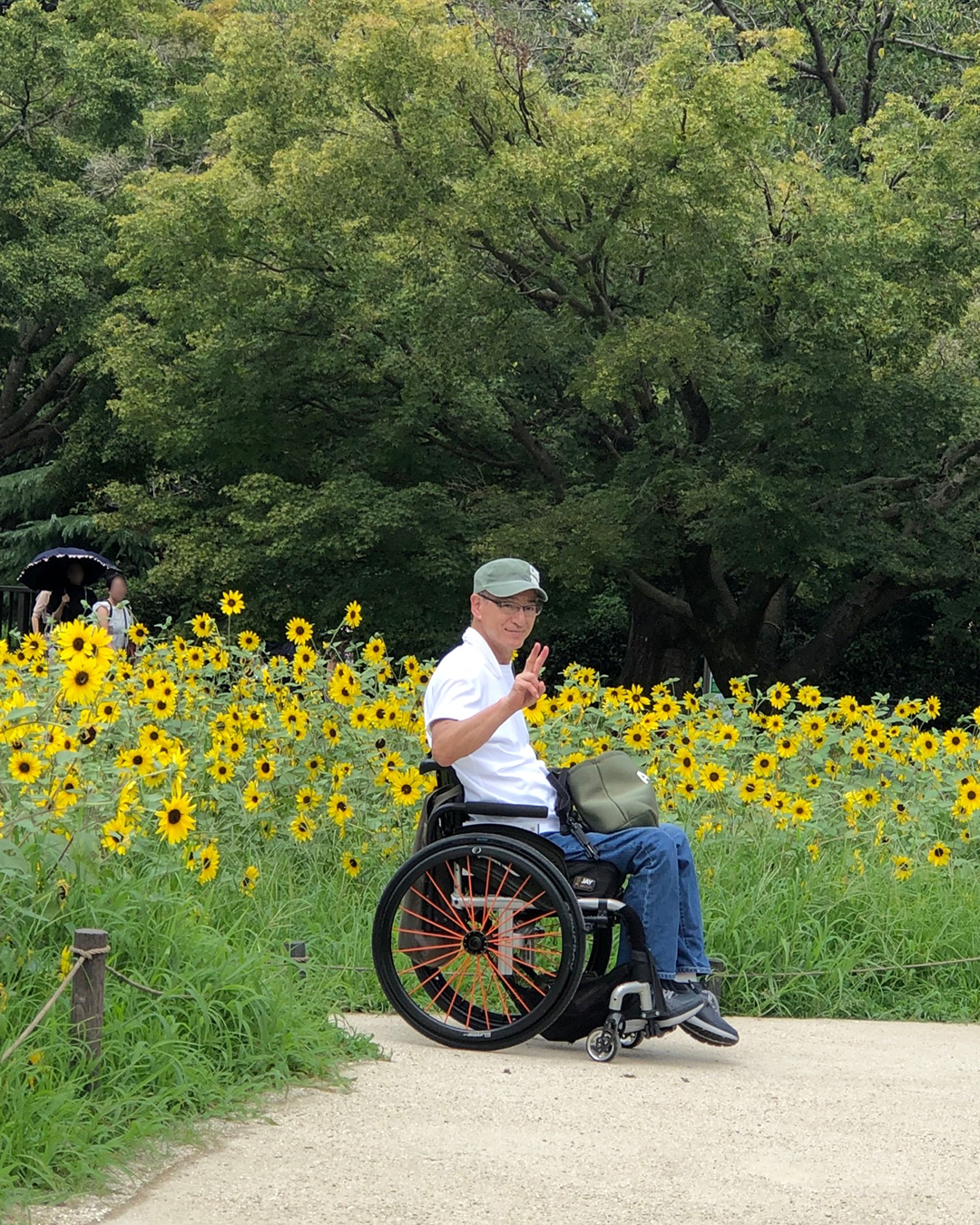 一面に咲いているヒマワリサンフィニティの中でピースをしている筆者の写真