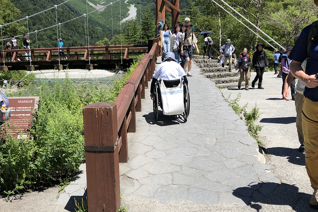 河童橋を渡るためにスロープを上る車いすの女性