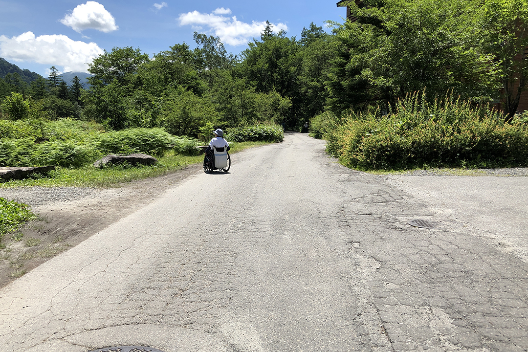 そのまま道を進む車いすの女性