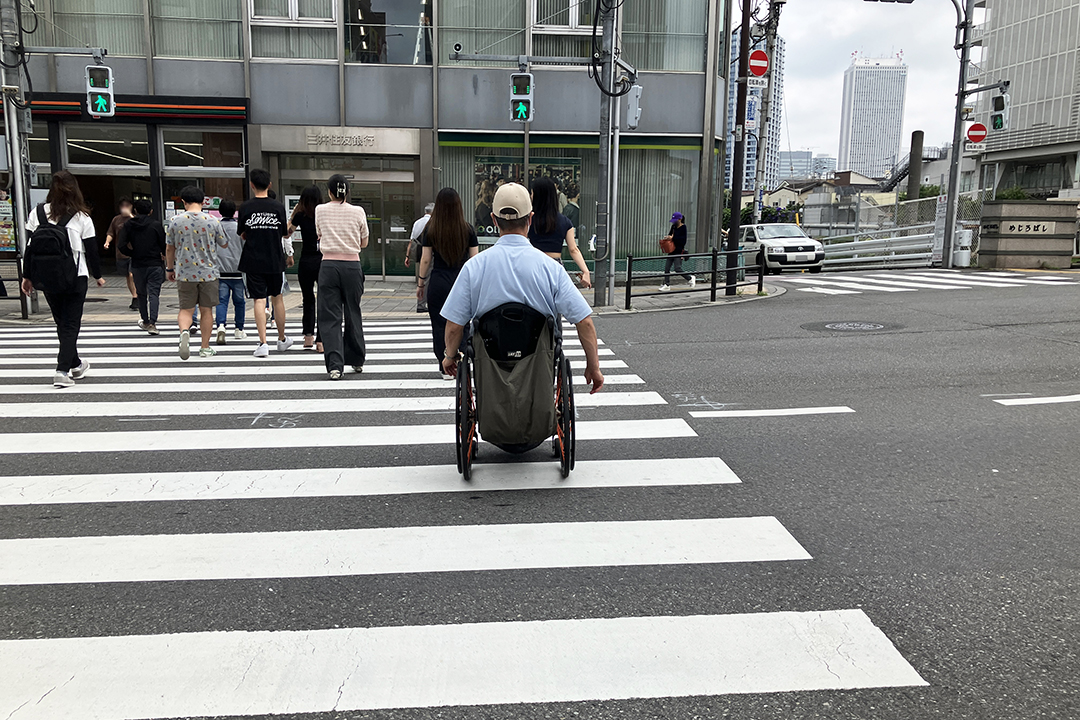 車いすの筆者が横断歩道を渡っている途中の写真