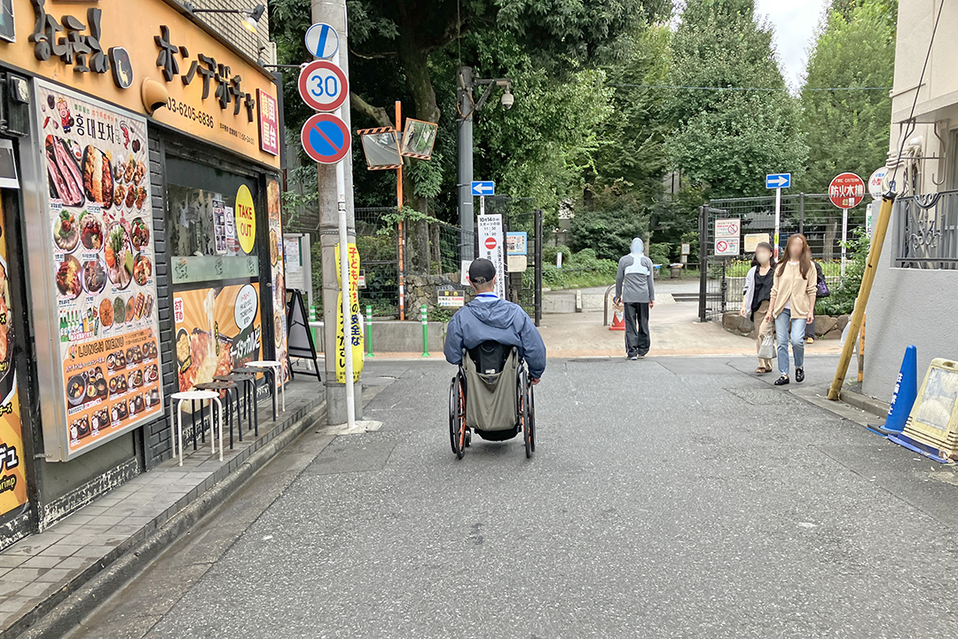 道路の先に西大久保公園の入口が見える写真