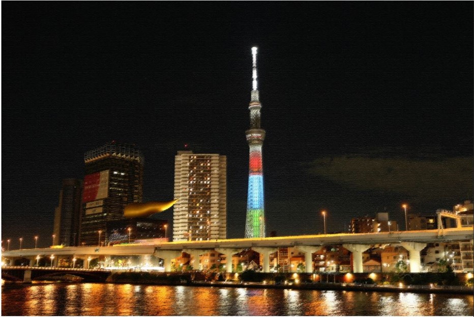 隅田川越しに高速道路とスカイツリーが見える夜景。アサヒビールの金の雲が光り輝く、隣にスカイツリーが赤青緑にライトアップされている