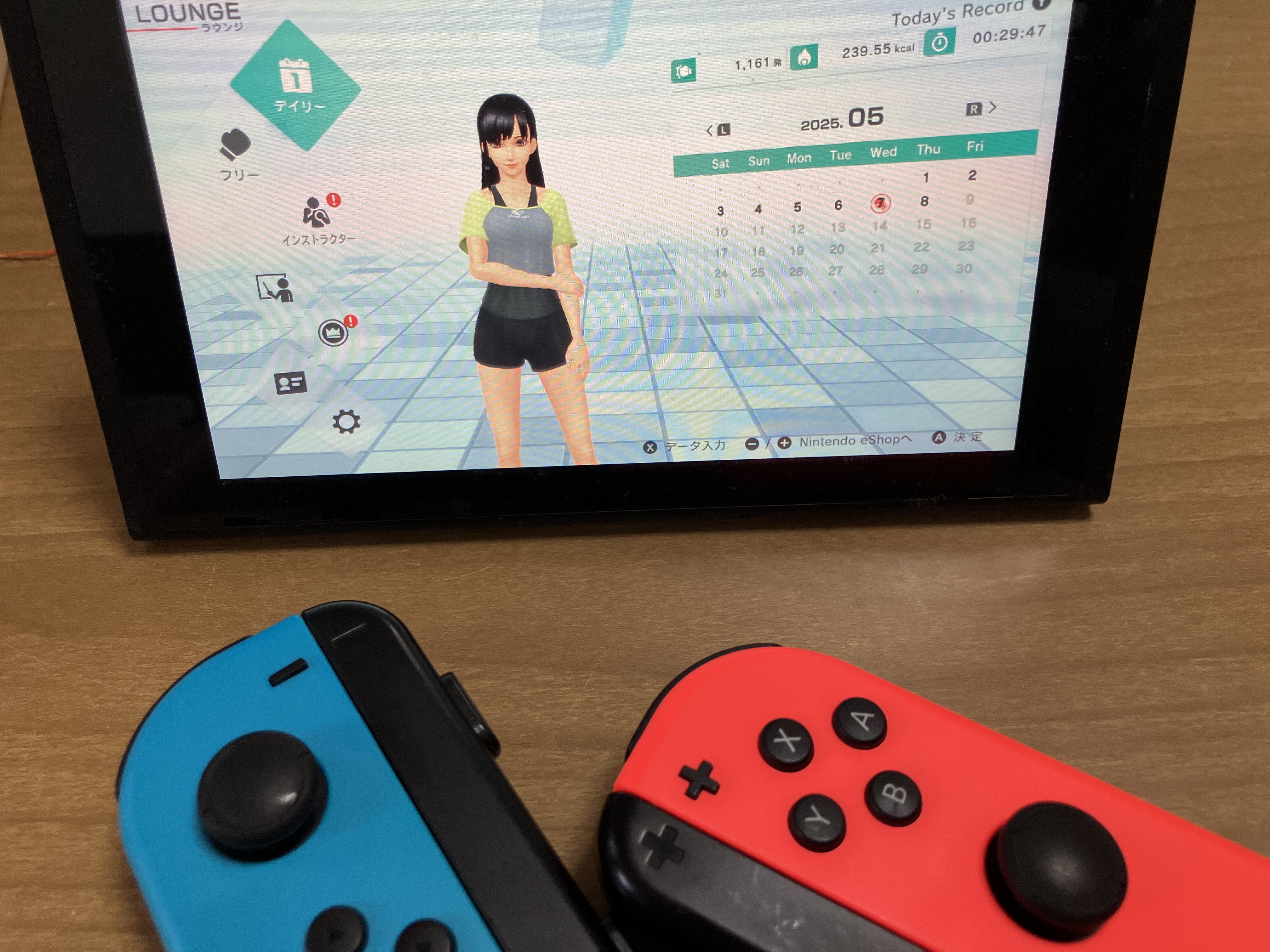 トレーニングウェアの女性キャラクターが映ったエクササイズゲームの画面。ゲーム機の手前にはコントローラーが置いてある。