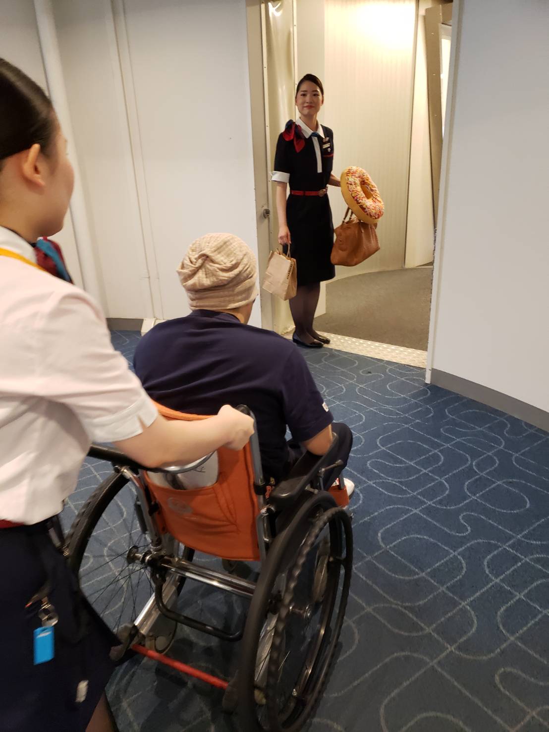 荷物を持ってくれている方と、車いすを押してくれる方、二人のCAさんに手伝ってもらっている