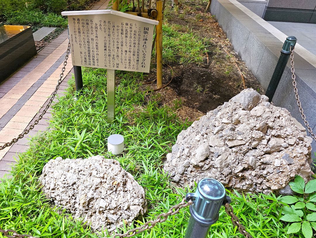 国家に詠われたさざれ石の立て看板 手前にはさざれ石 小石を石灰がくっつけて大きな岩になった 国家が作られた地方の石なのでこれは本物かも