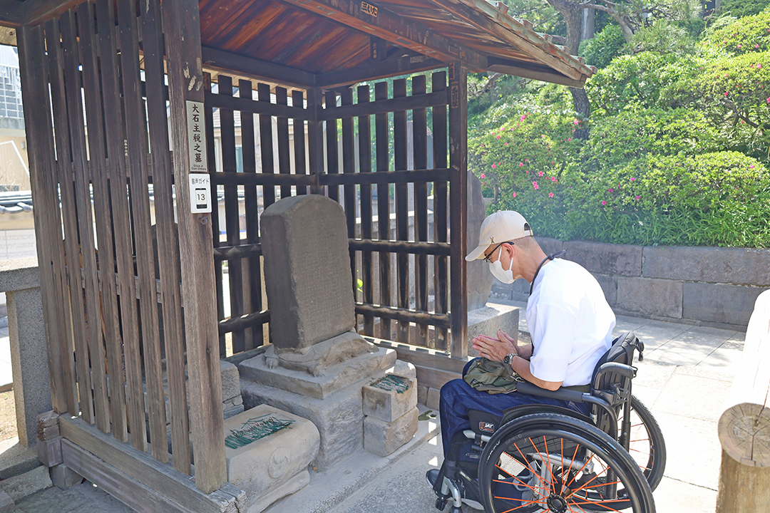 大石主税のお墓の前で手を合わせている筆者