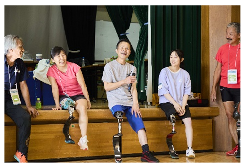 笑顔でインタビューを受ける義足の男性。隣の義足の女性も笑っていて、和やかな雰囲気。