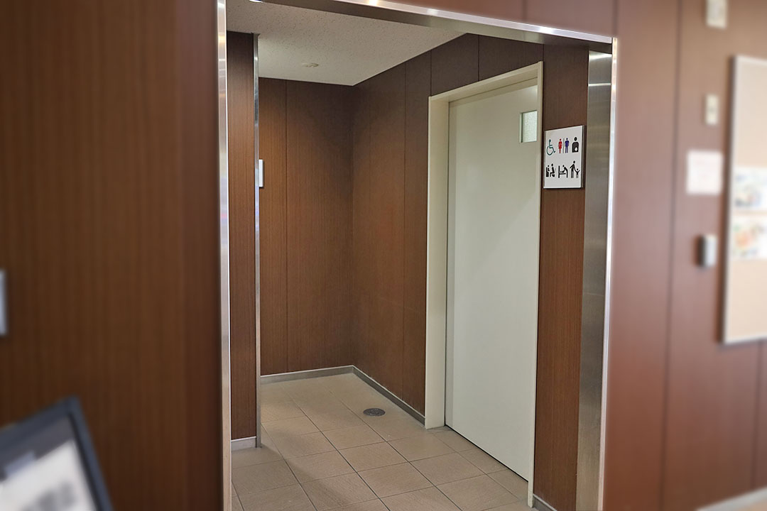 多目的トイレの入り口が写っており、木目調の壁と明るい照明で、温かみが感じられます。