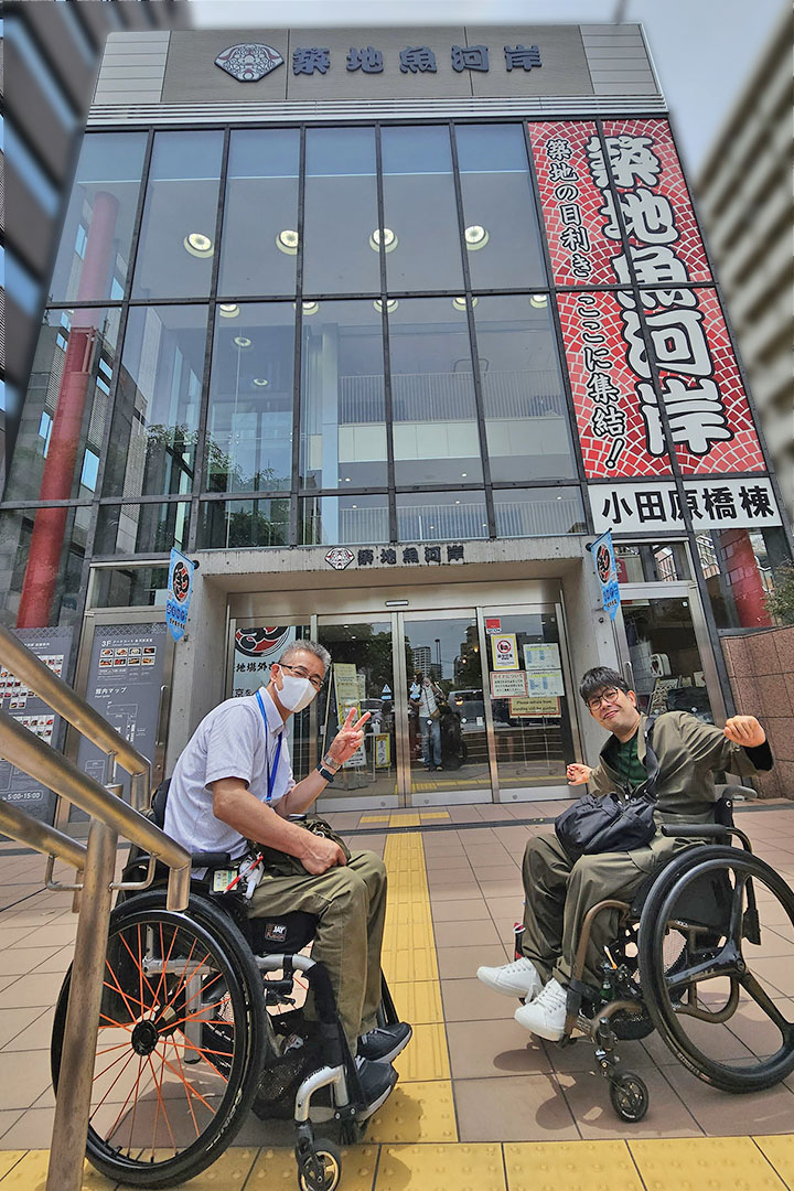 築地魚河岸の建物の前で、車いすの利用者同士がリラックスした雰囲気で、楽しそうにポーズを取っています。