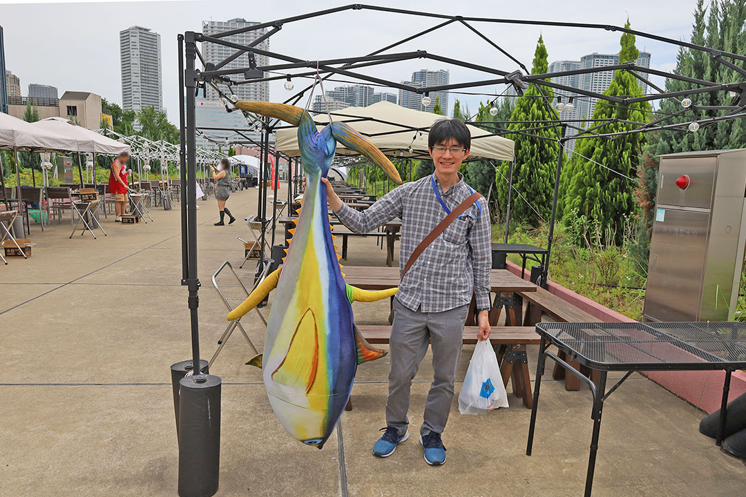 大きな魚のオブジェを持っている。スタッフY！