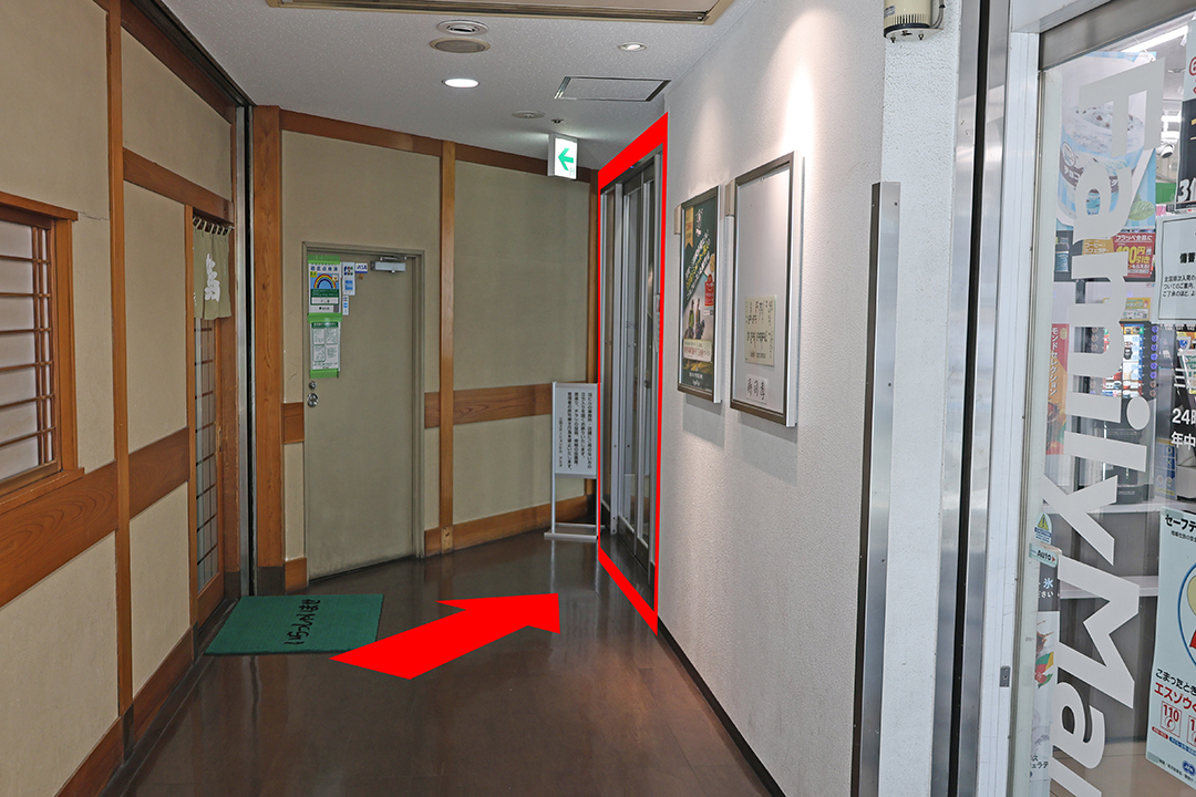 ビルの中に入りすぐ右側にコンビニの入口があり、その先にあるドアの入口を赤枠で示した写真