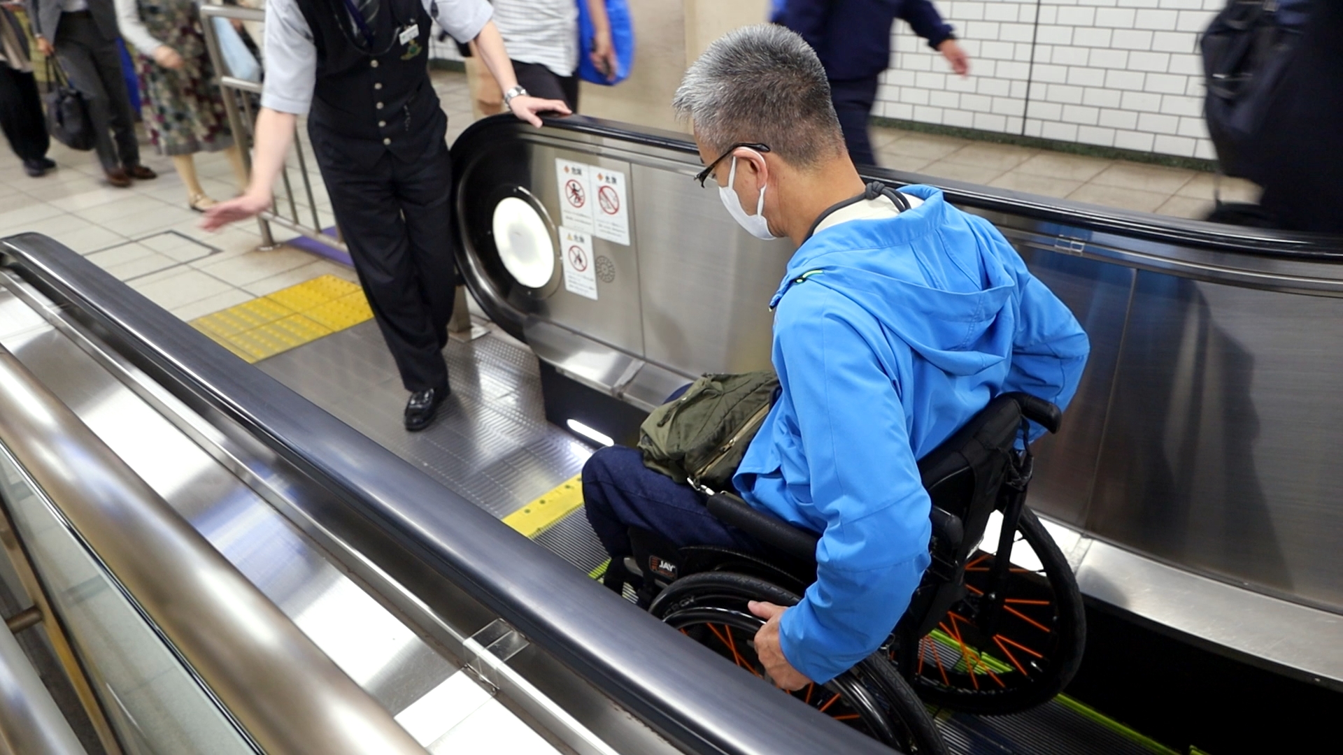 駅員に誘導されながら下りエスカレーターを降りる筆者