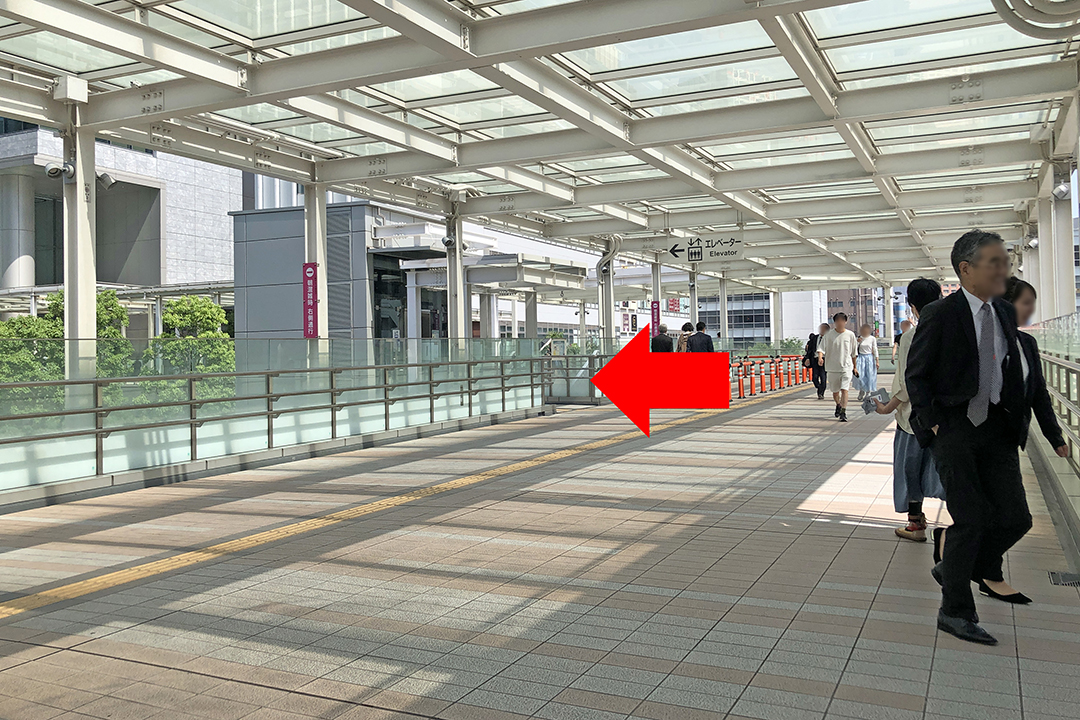 通路の先の左側にエレベーターがあるのを赤矢印で示している写真