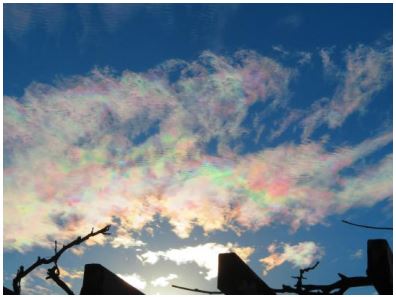 青空の白い雲が虹色に染まっている