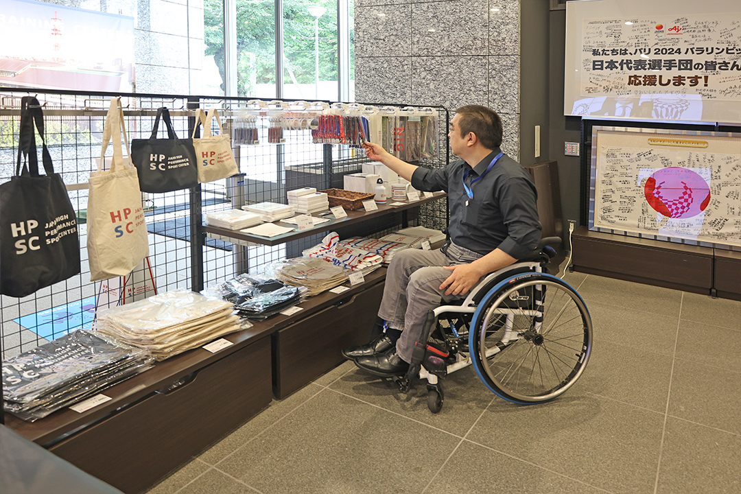 トートバック、ボールペンなどのグッズを前にどれを買おうかと悩んでいます