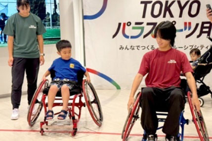 車いすのパラアスリートが子供にパラスポーツを教えている