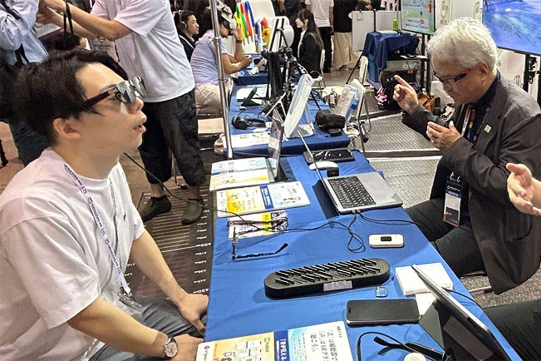 補聴グラスをかけて、声の字幕や手話言語映像が映るのを体験している