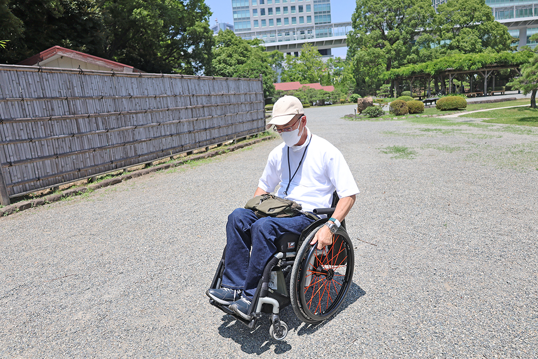 庭園内の砂利道を車いすの前輪を上げながら走る筆者