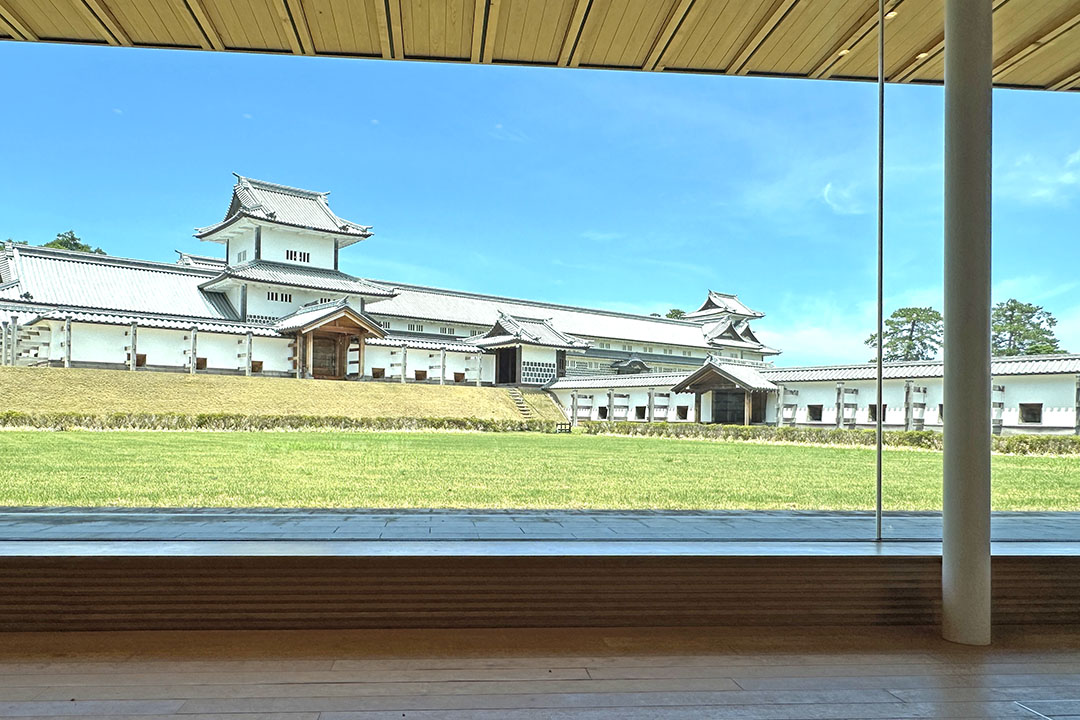 広い窓越しに美しい白壁の城と青い空が見渡せる景色です。木造の屋根やフロアの温かみが前景にあり、ゆったりとしたひと時を感じさせます。