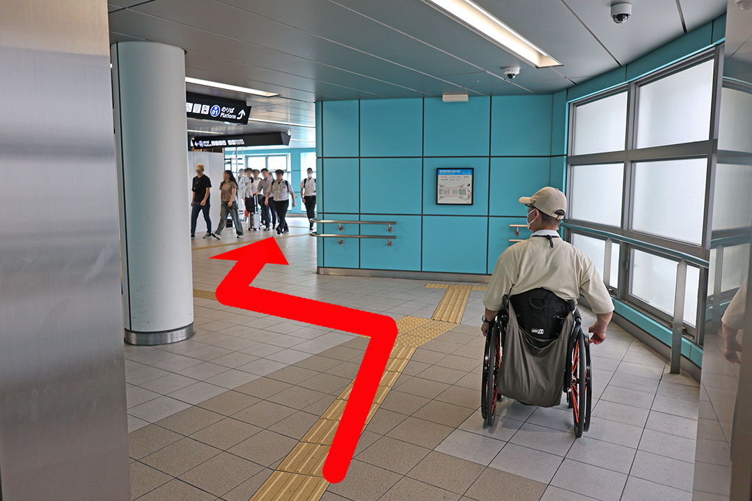 2階のペデストリアンデッキの通路に出る車いすの男性。