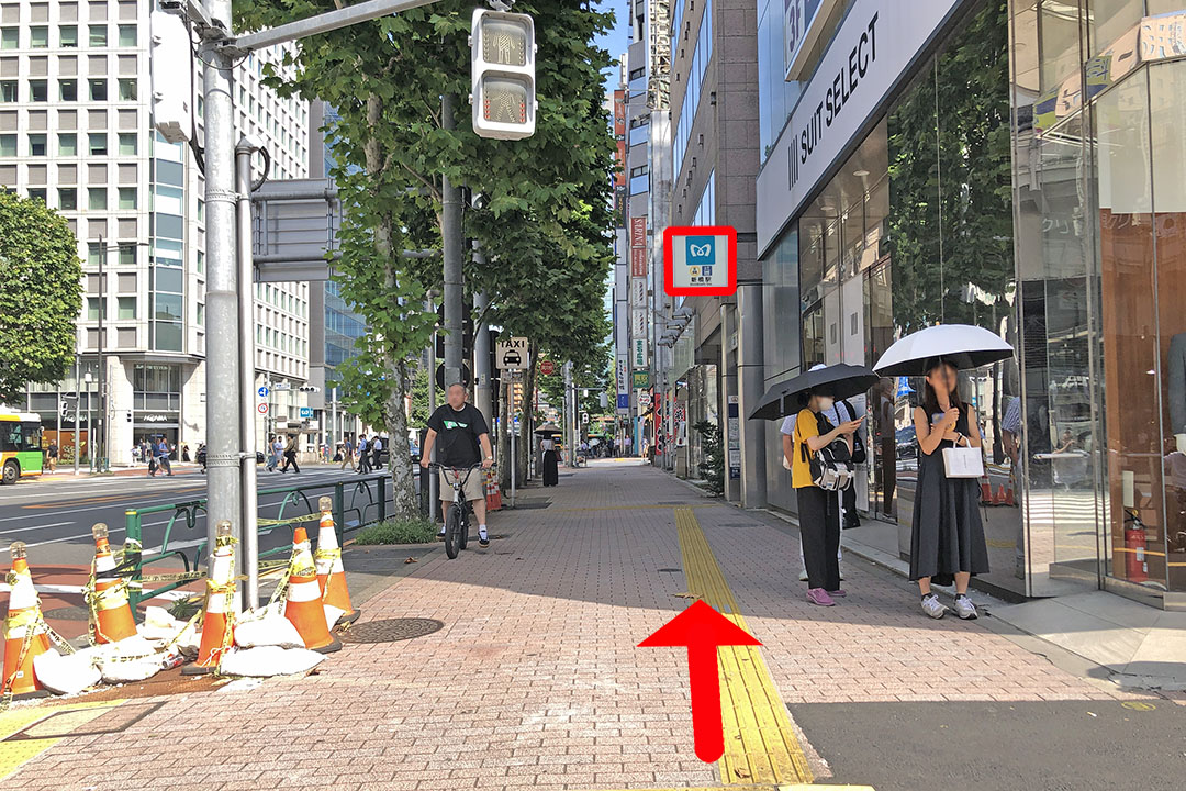 ビルの左側の歩道の先に東京メトロの看板が見える写真。