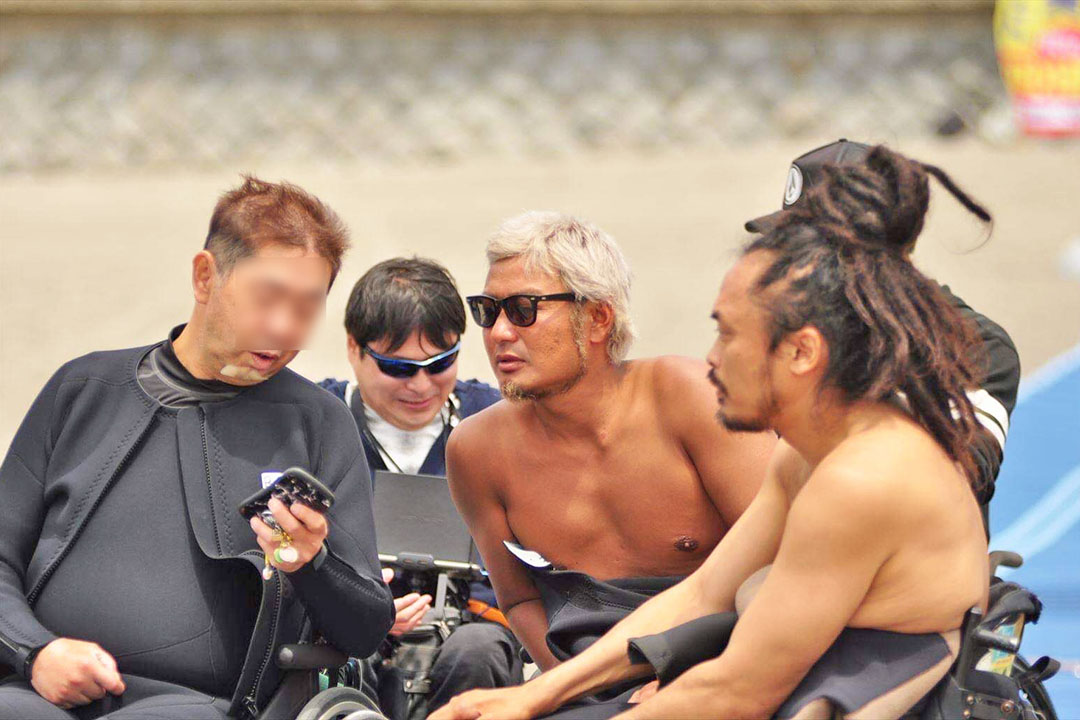 ウェットスーツ姿で、仲間同士の交流やコミュニケーションの楽しさが伝わってくる様子