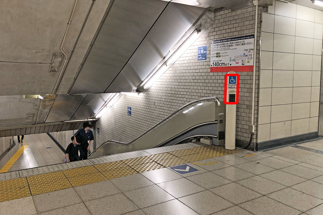 １つ目のエスカレーターの上側にあるインターフォンと階段を見下ろす写真