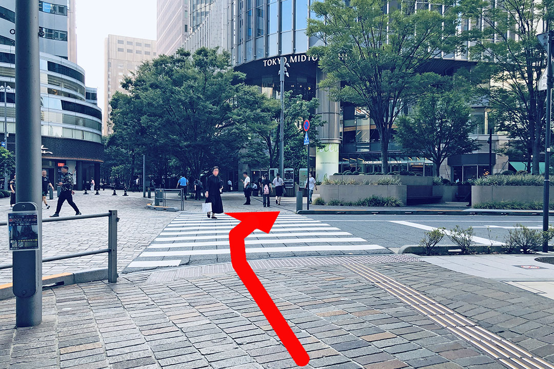 歩道から横断歩道の先に東京ミッドタウンの建物が見える写真