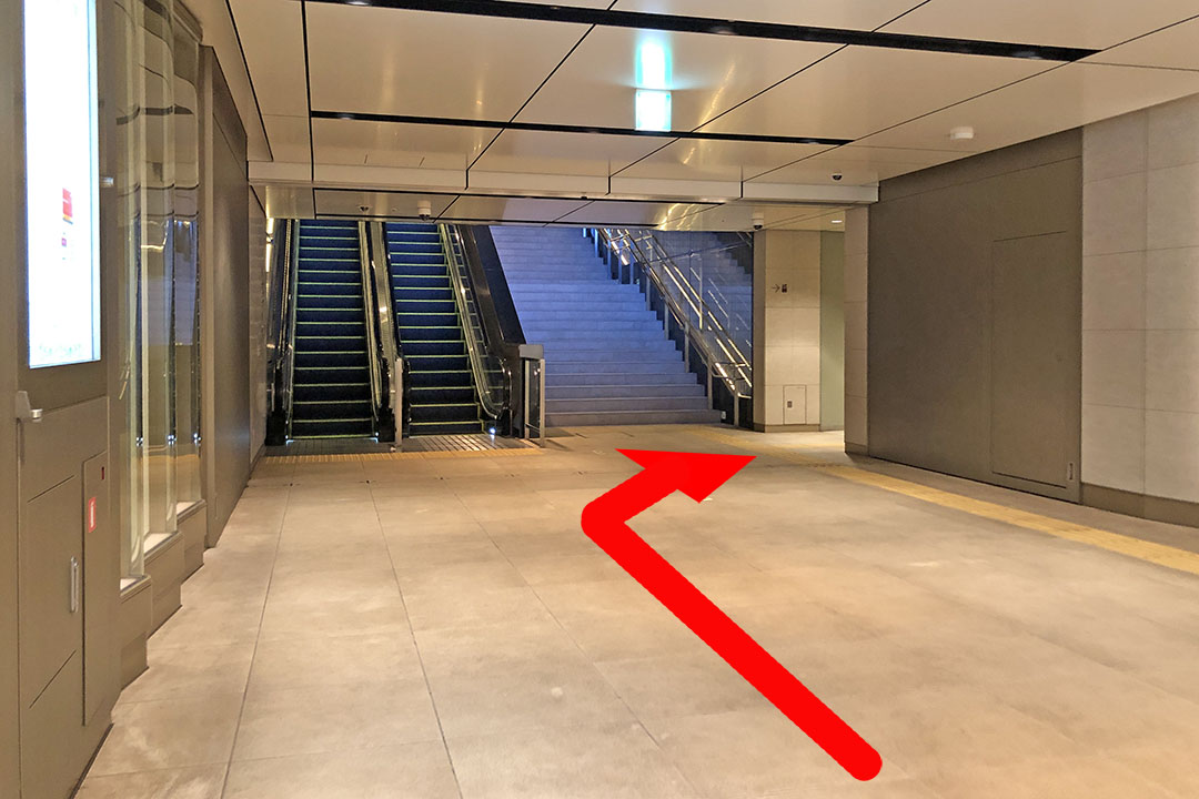 通路の突き当たりにある階段とエスカレーターの手前を右方向に行ける通路の写真