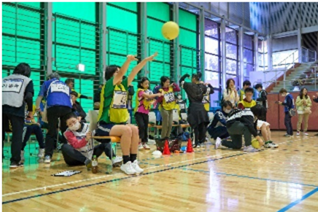 体力測定でボール投げを行っている様子。ボールを投げたときに椅子が動かないよう後ろで押さえている