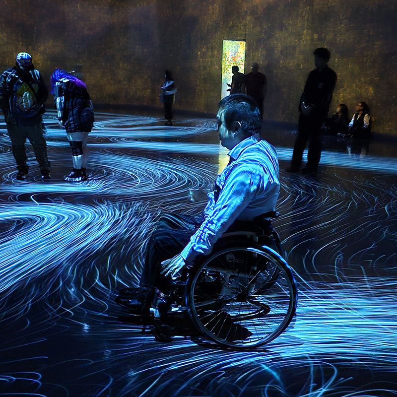 光の渦や流れの中で戯れている車いすの男性