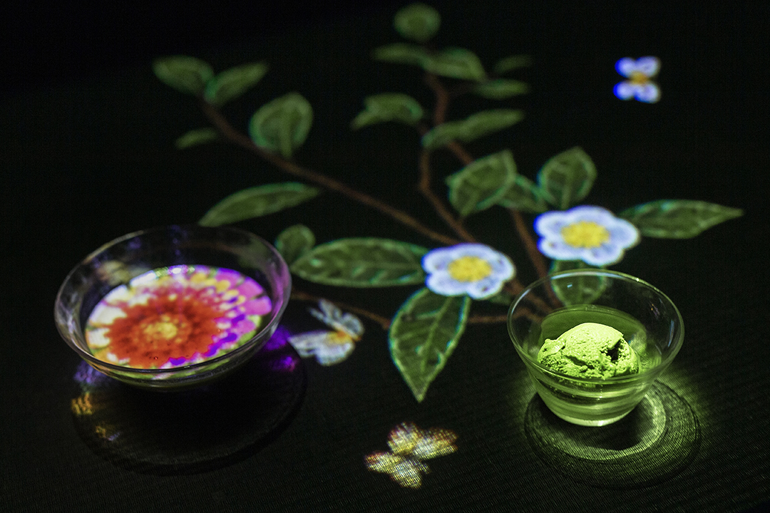 テーブルの左側は抹茶のグラスの中に花の映像が映し出され、右側には抹茶のアイス入りのグラスから茶の木の映像が生えてきている