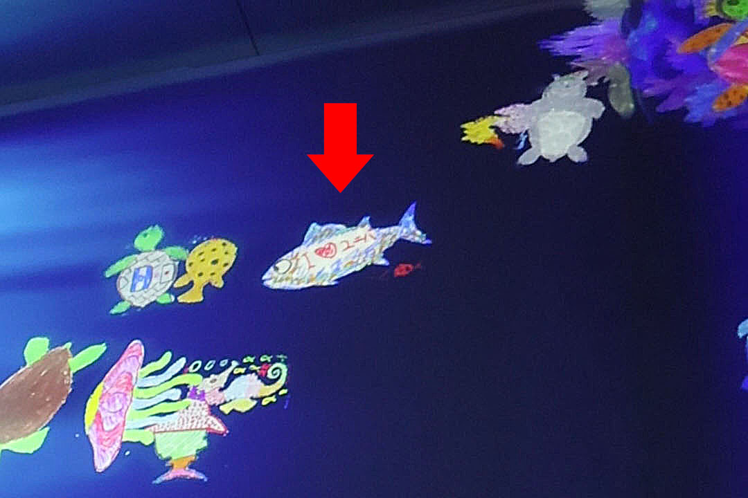 車いすの男性が描いた魚が泳いでいるようす