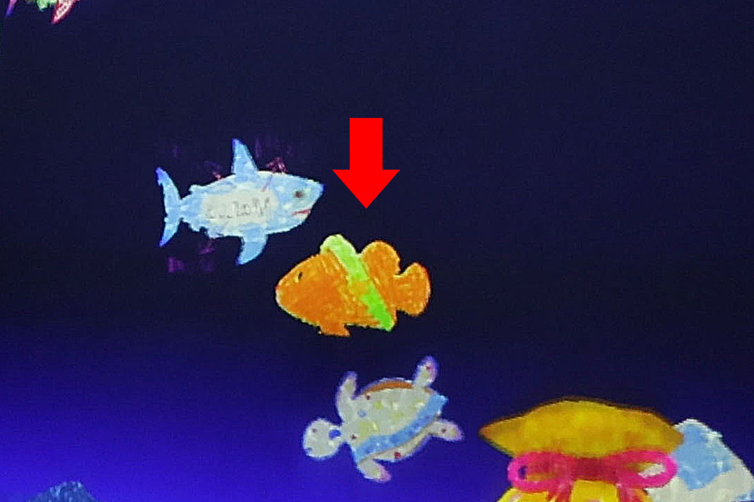 車いすの女性が描いた魚が泳いでいるようす