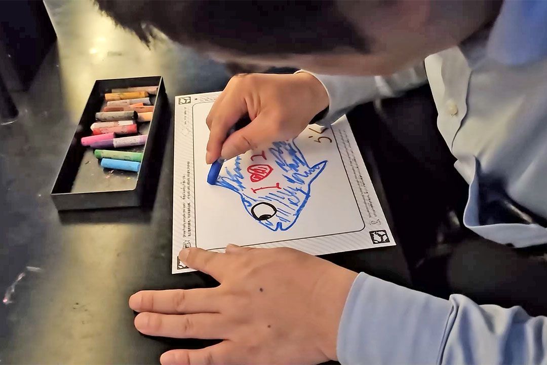 車いすの男性が魚の絵を描いているようす