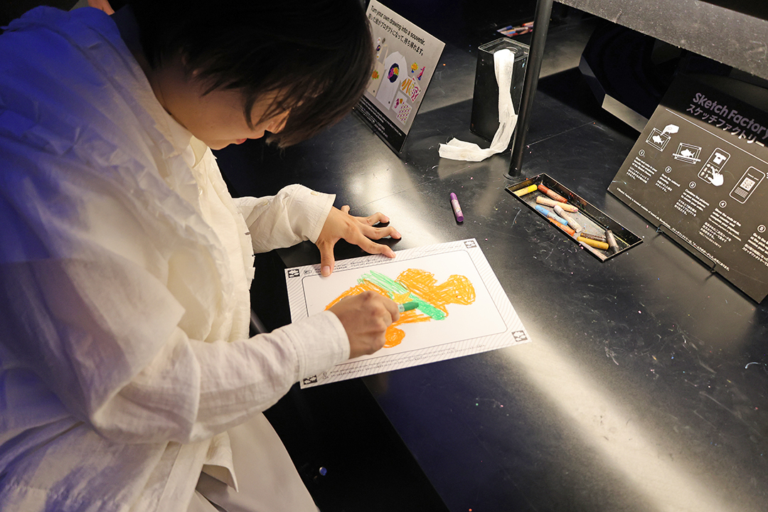 車いすの女性が魚の絵を描いているようす