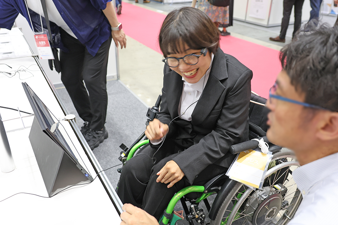 ジンズアシストを取り付けたメガネをかけ、体験をしている車いすの女性