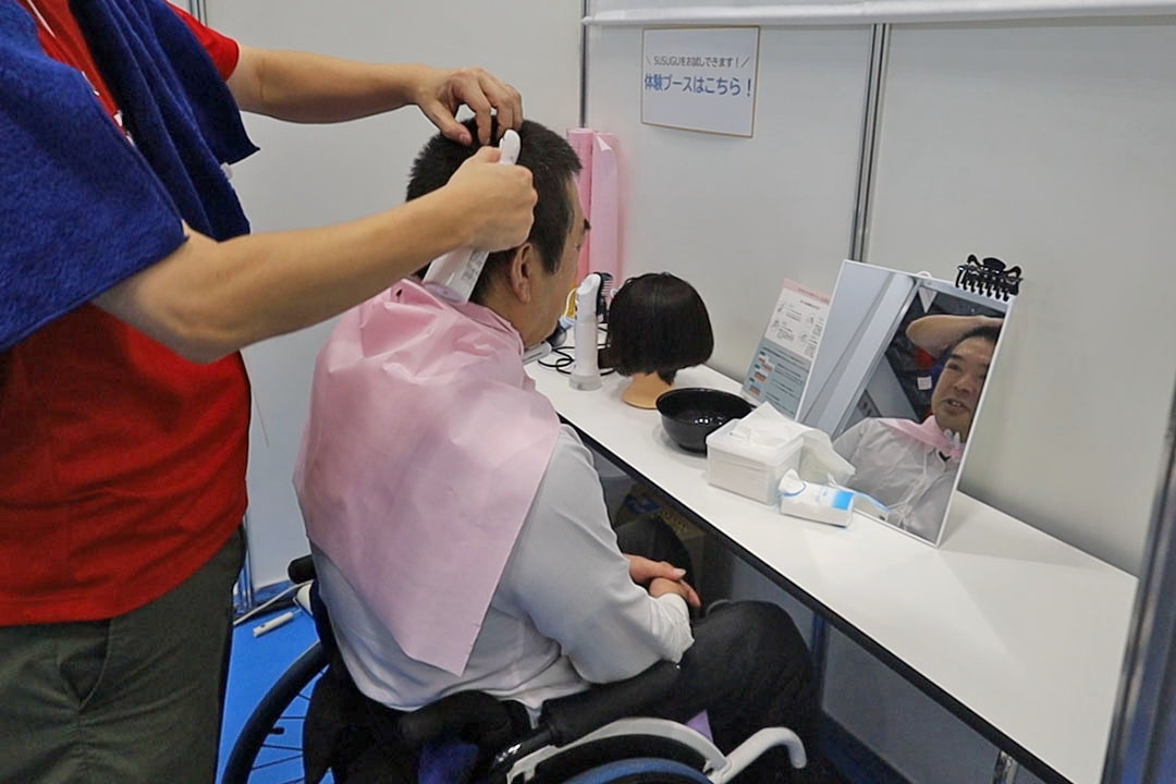 ミストシャンプーを頭にかけ洗髪を体験している車いすの男性