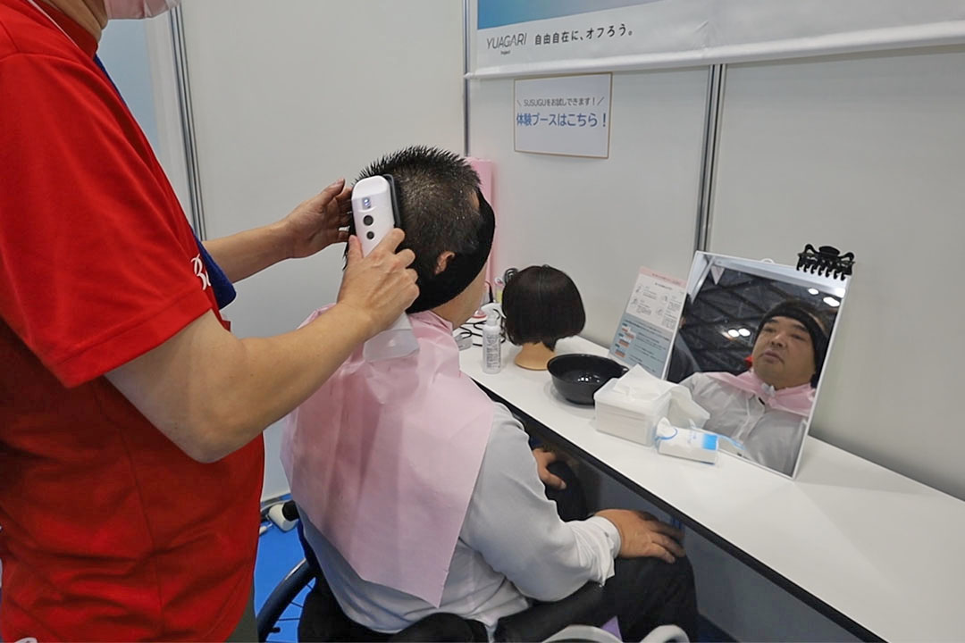 ミストブラシで洗髪を体験している車いすの男性