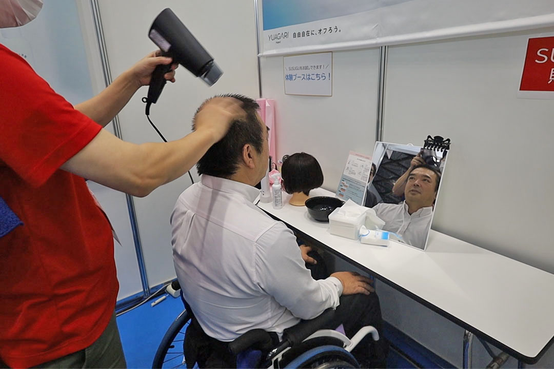 仕上げはドライヤーで頭を乾かしている車いすの男性