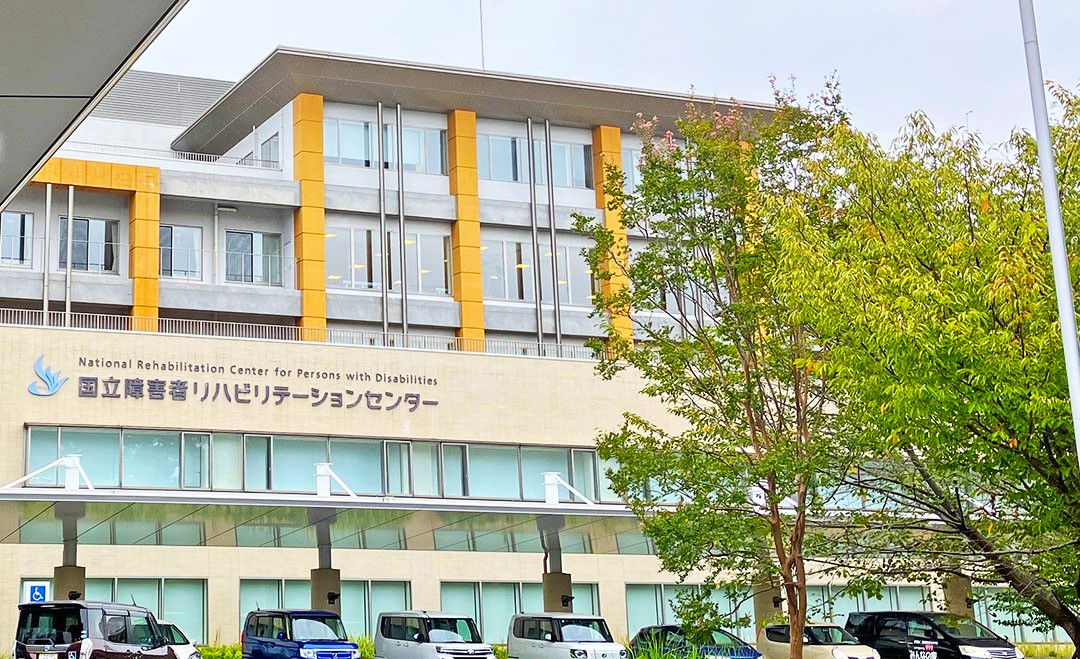 国リハの前景図　薄いオレンジ色のタイルと2階部分には濃いオレンジのストライプが特徴的