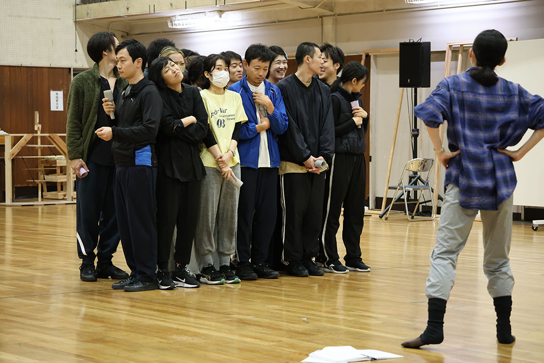 満員乗車の場面の演技の説明を演出の方から聞く役者たち