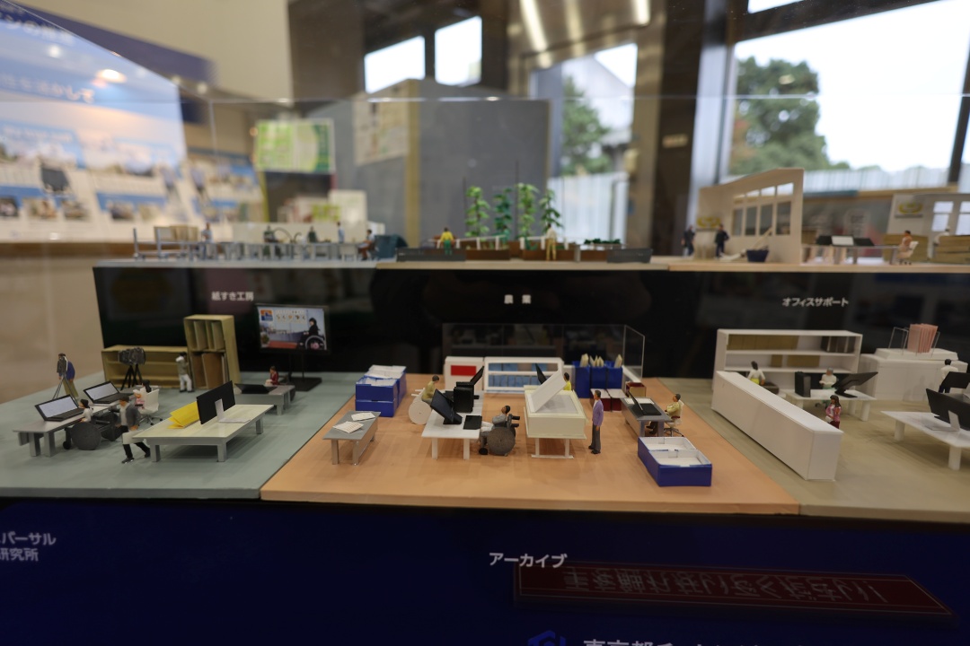 アーカイブのオフィスには巨大なスキャナーを操作する社員やパソコン操作をする車いすの社員がミニチュア化されている