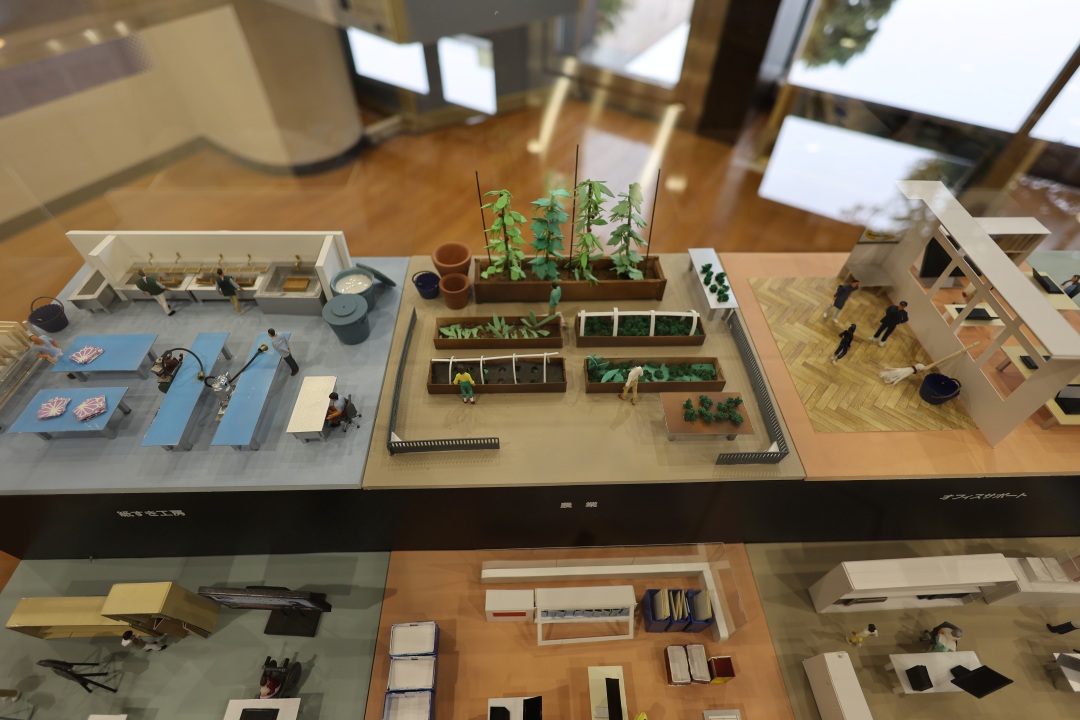 水槽や作業台のある紙すき工房、プランターで野菜を栽培している農園のジオラマ