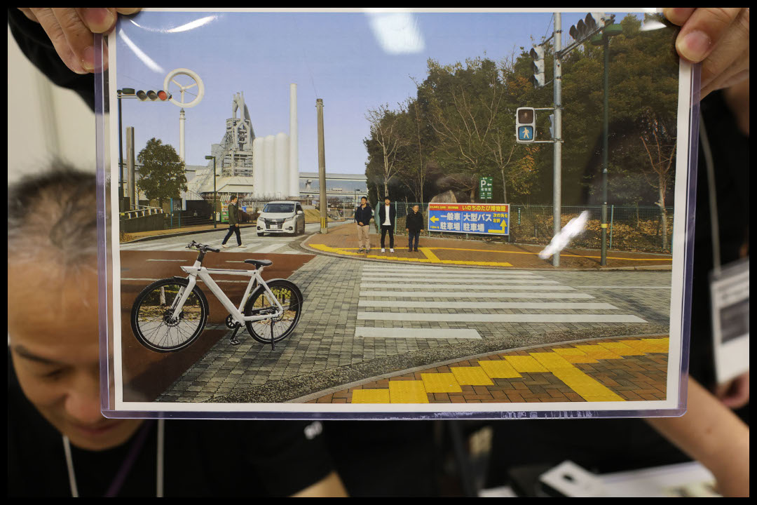 アイナビの動作を確認するためのパネル　手前に点字ブロック　その先に自転車と横断歩道　右奥に歩行者用信号機