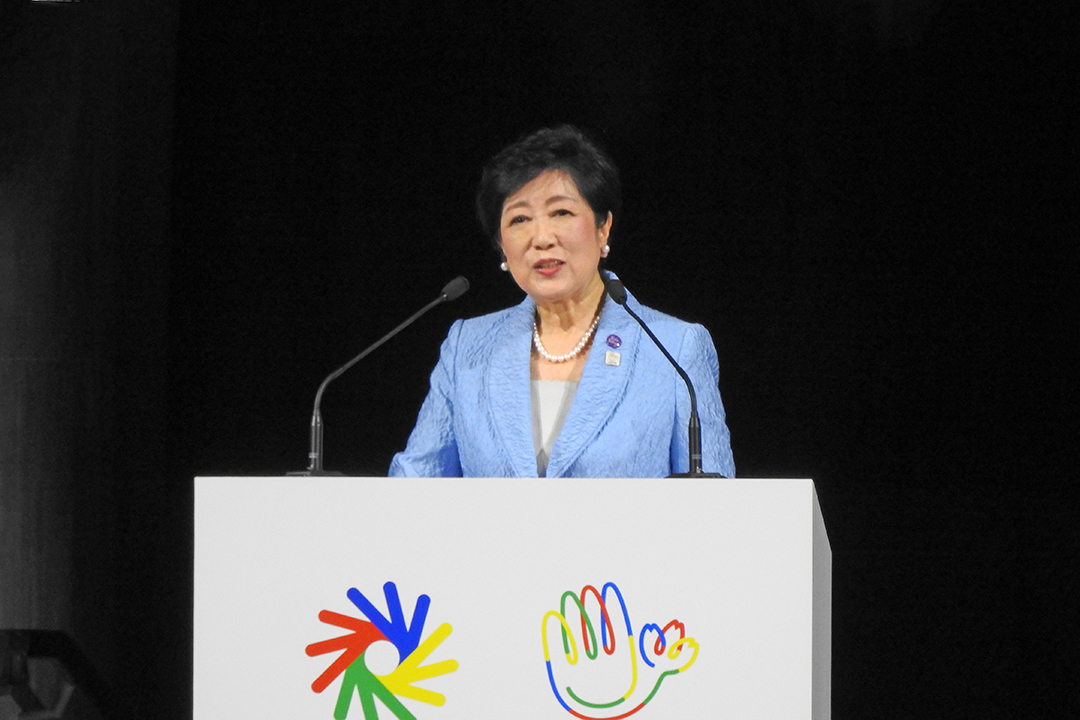 きれいな水色のジャケットを着て挨拶しています