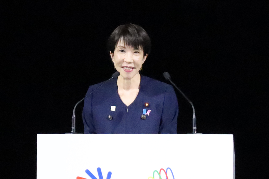 紺色の衣装を着て挨拶しています